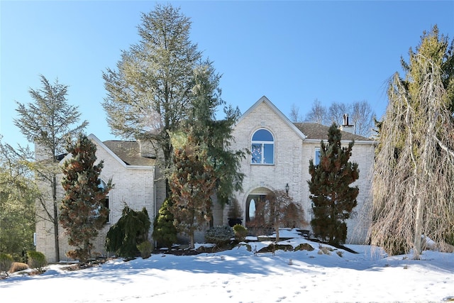 view of front of home featuring brick siding and a chimney