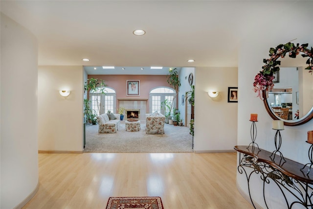 entryway with a warm lit fireplace, recessed lighting, wood finished floors, and baseboards