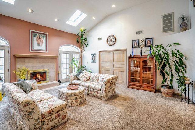 living area featuring high vaulted ceiling, a skylight, visible vents, and carpet flooring