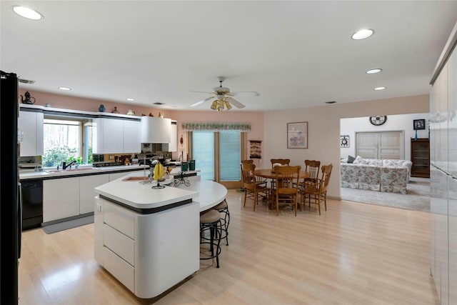 kitchen with dishwasher, an island with sink, light wood-type flooring, and white cabinets