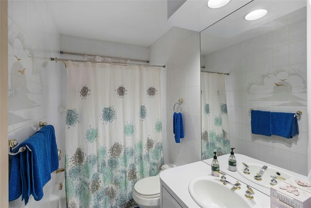 bathroom with toilet, shower / tub combo with curtain, tile walls, and vanity