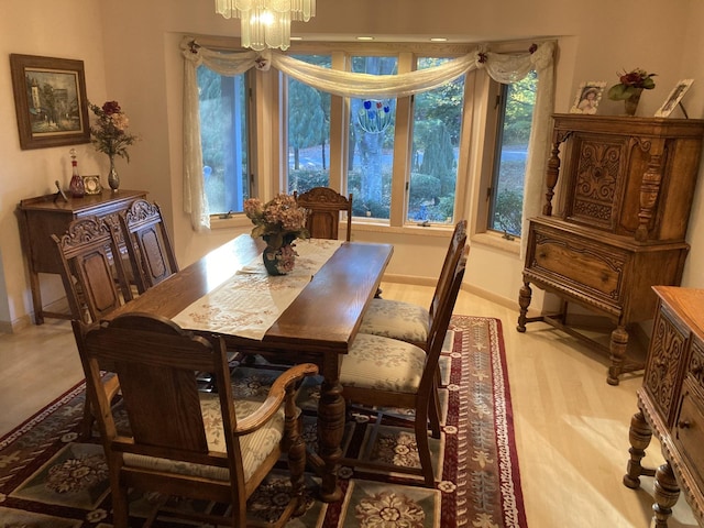 dining space featuring baseboards, light wood finished floors, and a notable chandelier