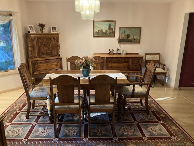 dining room with baseboards, a notable chandelier, and wood finished floors