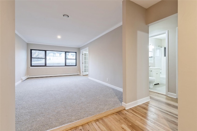 empty room featuring crown molding, light wood-style floors, a baseboard heating unit, light carpet, and baseboards