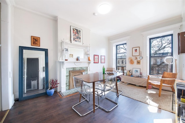 dining space with ornamental molding, a premium fireplace, and wood finished floors