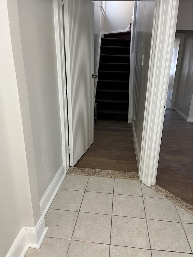 hallway with light tile patterned flooring, stairway, and baseboards