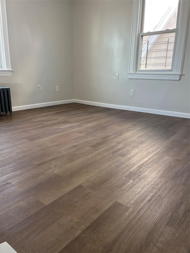 spare room with dark wood-style floors, radiator, and baseboards