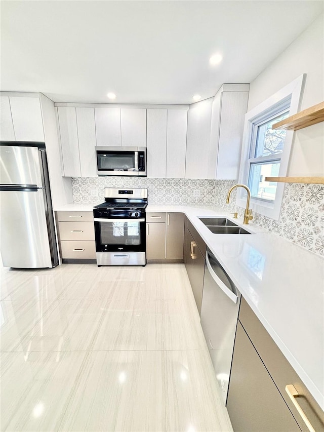 kitchen featuring tasteful backsplash, light countertops, appliances with stainless steel finishes, modern cabinets, and a sink