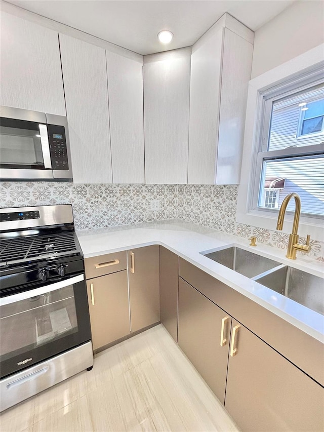 kitchen with decorative backsplash, light countertops, appliances with stainless steel finishes, and a sink