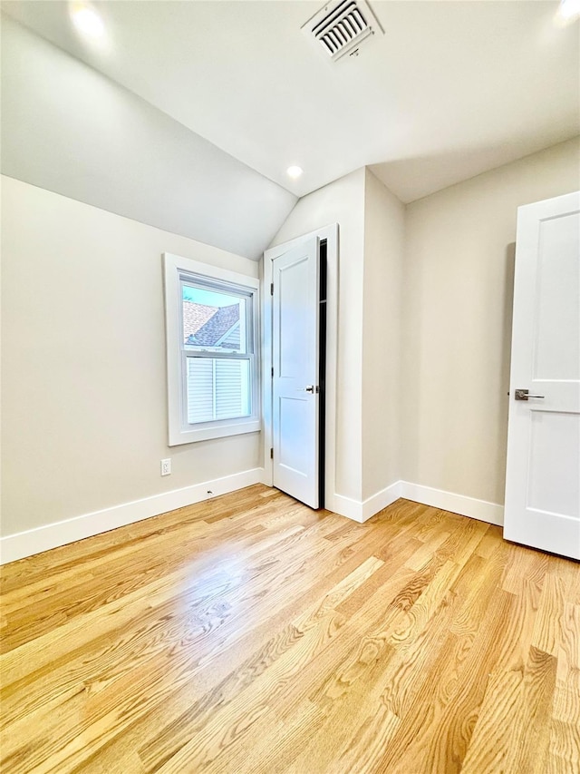 interior space featuring visible vents, light wood-style flooring, lofted ceiling, and baseboards