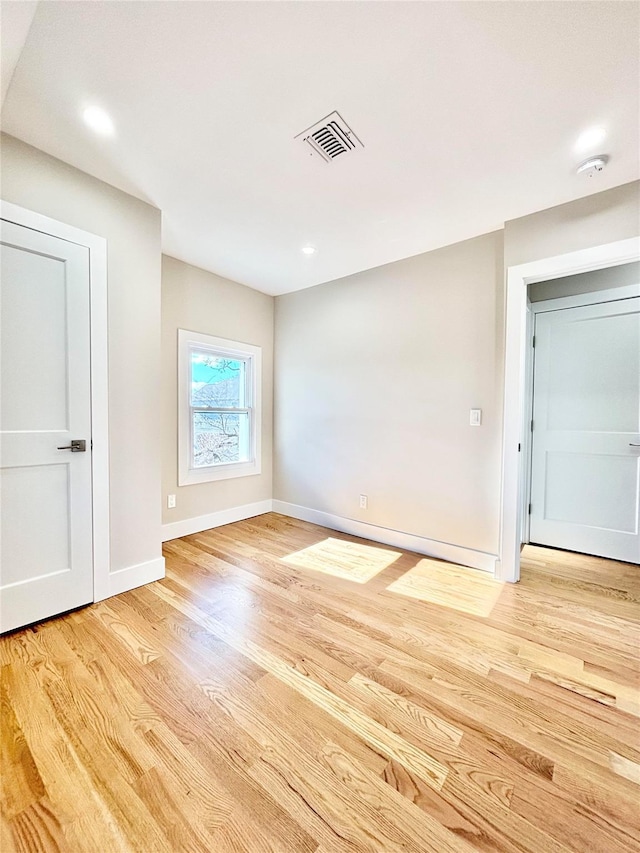 empty room featuring light wood-type flooring, visible vents, and baseboards