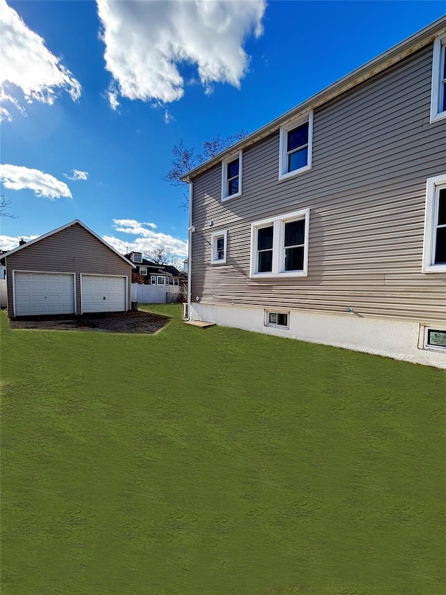 rear view of property featuring an outbuilding, a yard, and a detached garage