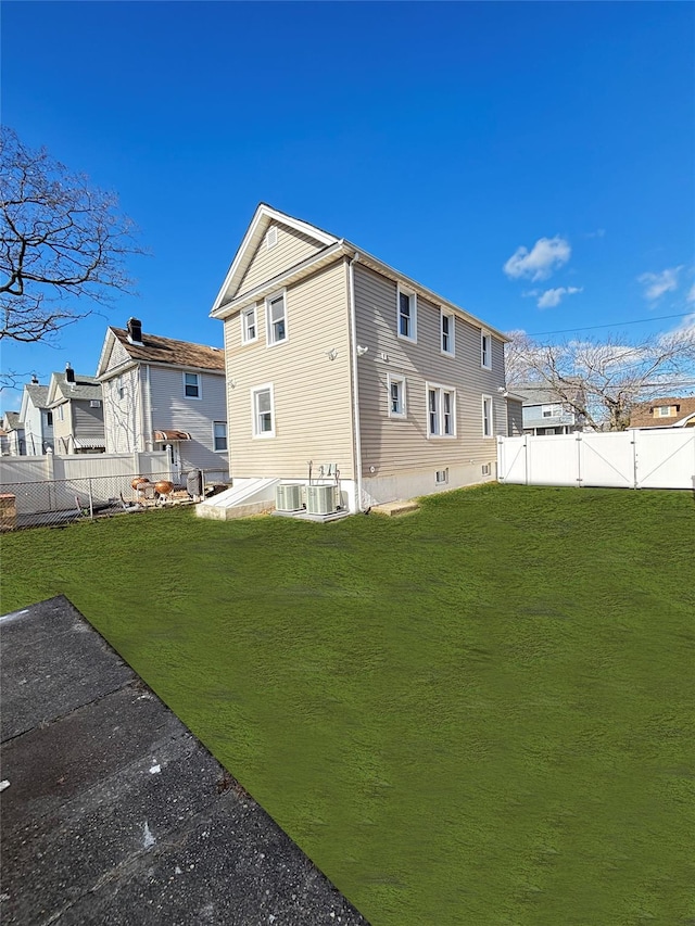 back of property with a gate, cooling unit, a lawn, and a fenced backyard