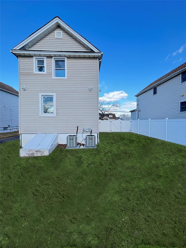 back of house with a fenced backyard, cooling unit, and a yard