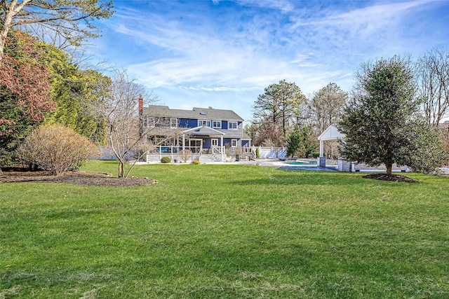 back of property featuring a chimney, an outdoor pool, and a yard