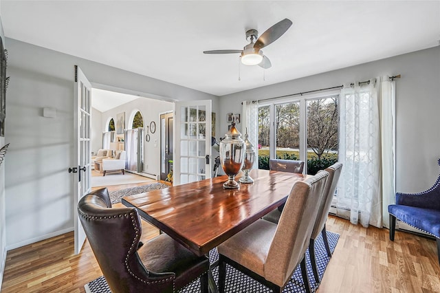 dining space featuring light wood finished floors, ceiling fan, baseboards, and french doors