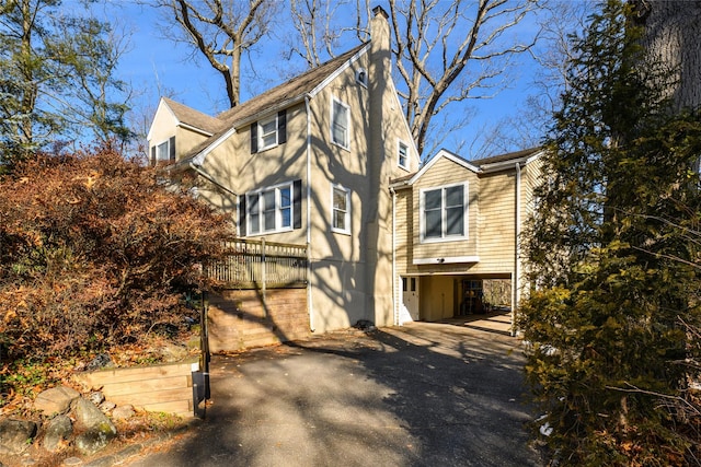 exterior space with driveway, a chimney, and a carport