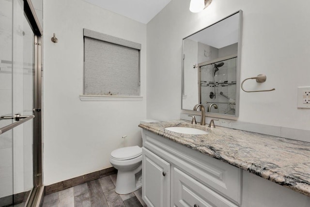 full bathroom with baseboards, toilet, wood finished floors, vanity, and a shower stall