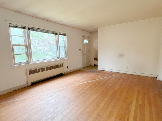 interior space with light wood finished floors, baseboards, and radiator heating unit