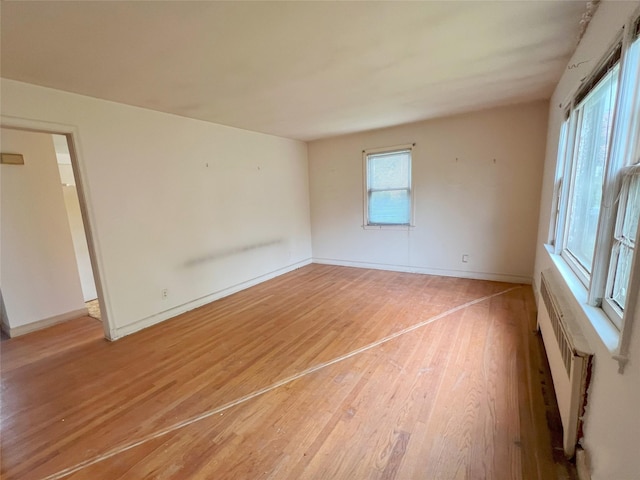 unfurnished room featuring light wood-style flooring, a wall mounted AC, and baseboards