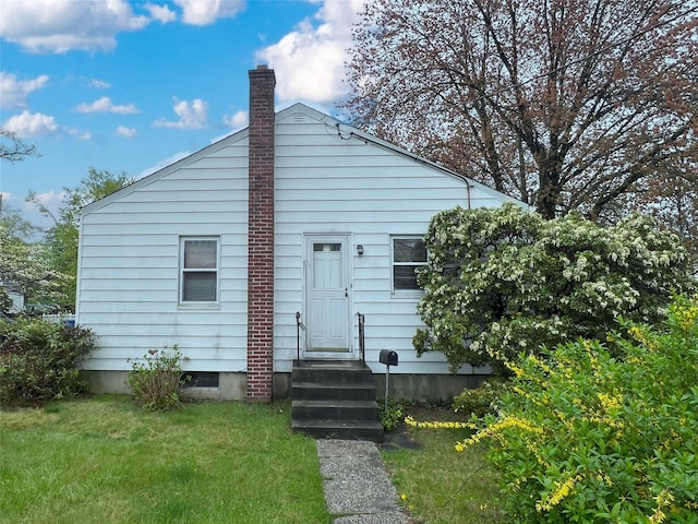 rear view of house with a chimney and a lawn