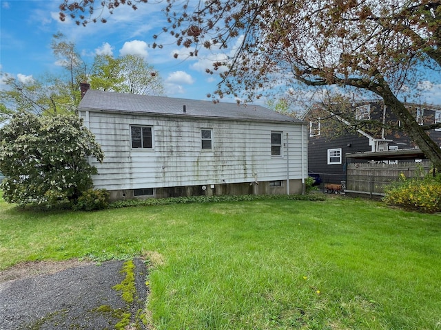 back of property with a chimney, fence, and a lawn