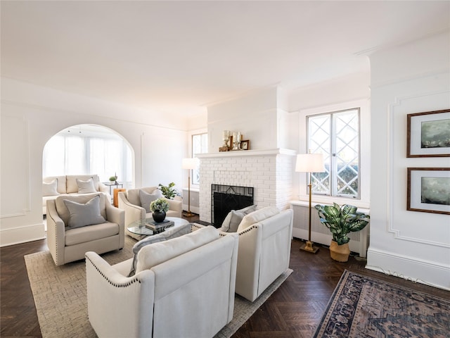 living area featuring radiator heating unit, a fireplace, and arched walkways