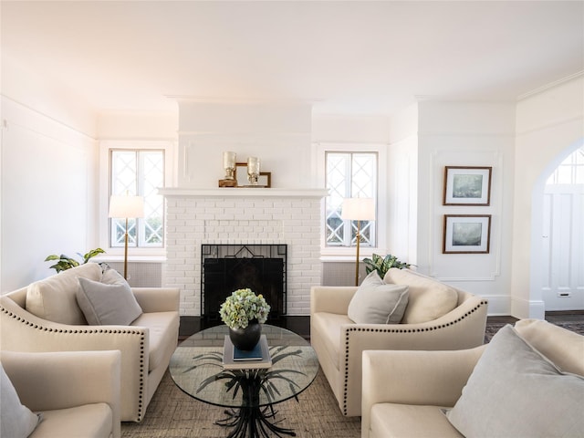 living room with a brick fireplace, baseboards, and wood finished floors