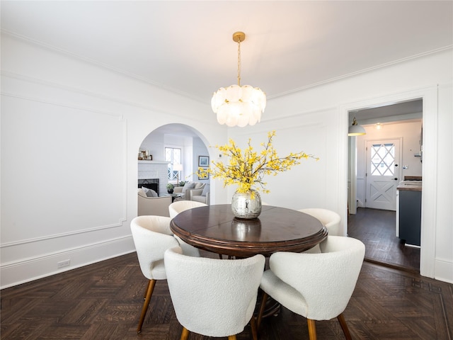 dining room featuring a fireplace, a chandelier, and arched walkways