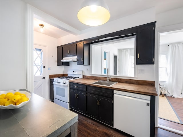 kitchen with under cabinet range hood, white appliances, butcher block countertops, a sink, and dark wood finished floors