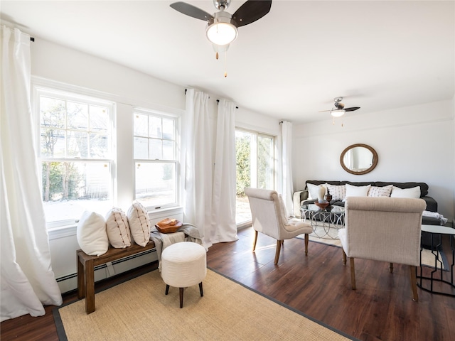 living area featuring dark wood-style floors, a baseboard heating unit, and ceiling fan