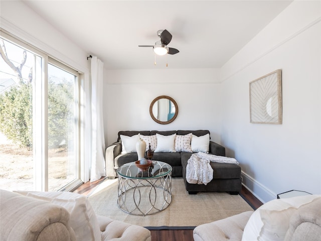 living area featuring ceiling fan, baseboards, and wood finished floors