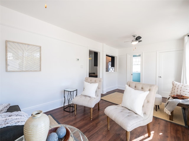 sitting room featuring dark wood-style flooring, ceiling fan, and baseboards