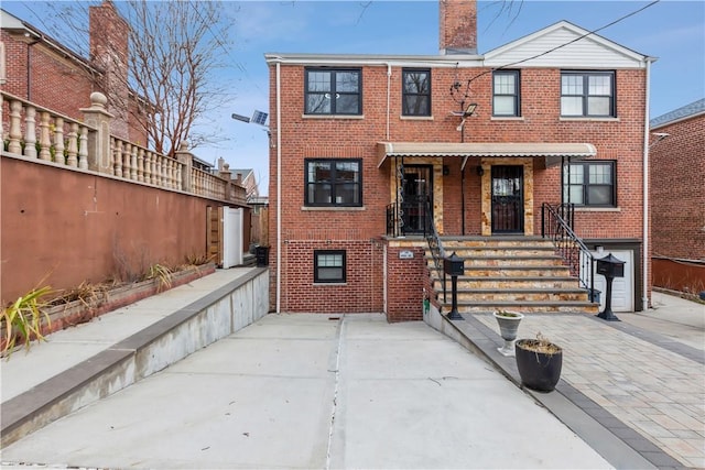 view of front facade featuring brick siding and a chimney