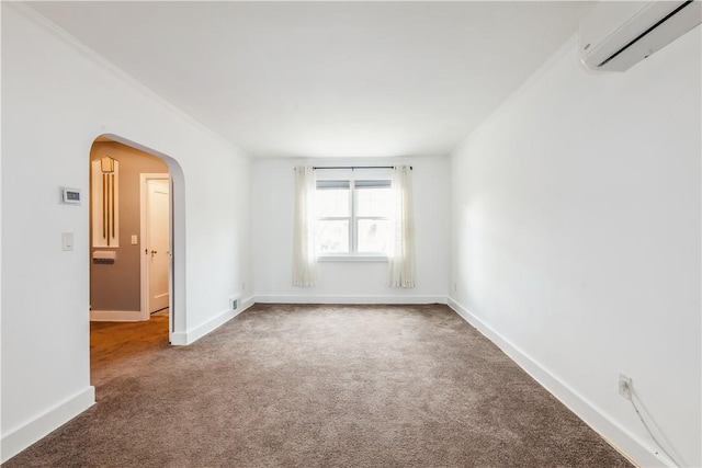 carpeted spare room featuring arched walkways, an AC wall unit, and baseboards