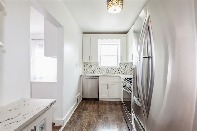 kitchen featuring dark wood-style floors, backsplash, appliances with stainless steel finishes, white cabinets, and light stone countertops