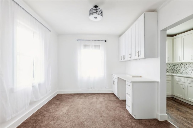 interior space with light colored carpet, white cabinetry, baseboards, light countertops, and decorative backsplash