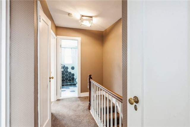 hallway with light colored carpet and an upstairs landing