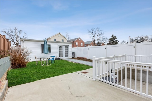 back of house featuring a patio area, a fenced backyard, french doors, and a yard