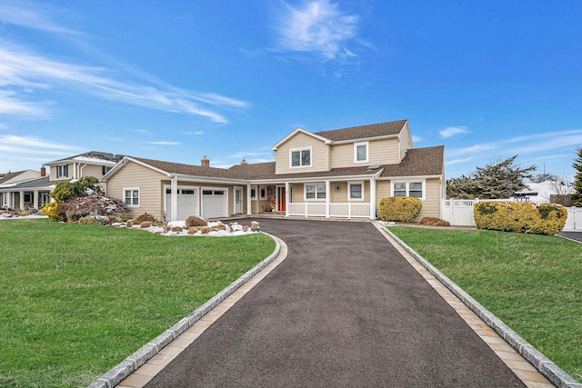 traditional home with a garage, driveway, a chimney, fence, and a front lawn