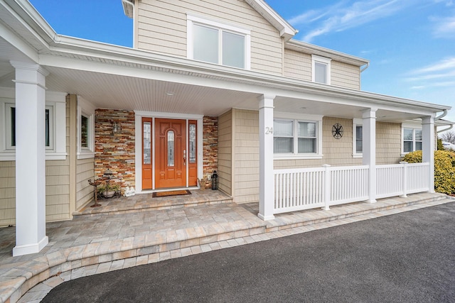 view of exterior entry with stone siding and a porch