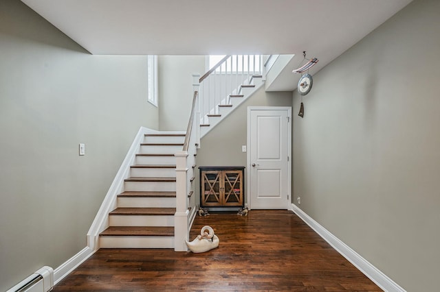 stairway featuring baseboards, a baseboard heating unit, and wood finished floors