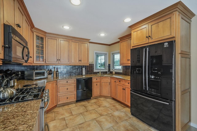 kitchen featuring black appliances, light stone counters, glass insert cabinets, and a toaster