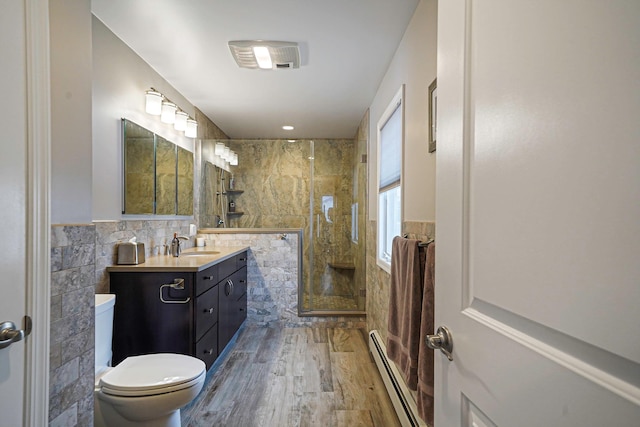 full bath featuring tile walls, toilet, baseboard heating, a shower stall, and wood finished floors