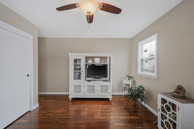 unfurnished living room featuring dark wood-type flooring, baseboards, and a ceiling fan