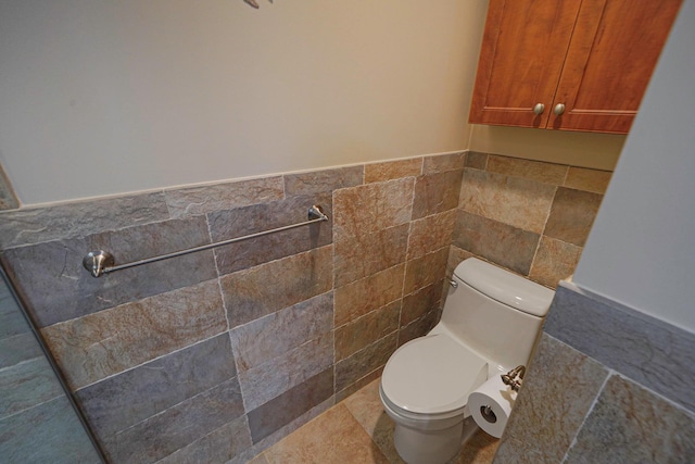 bathroom with wainscoting, tile walls, and toilet