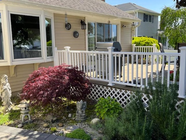 doorway to property featuring a deck and roof with shingles