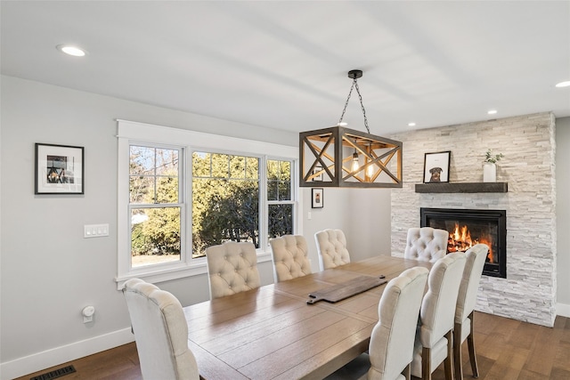 dining space with dark wood-style flooring, a fireplace, visible vents, and baseboards