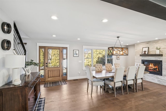 dining space featuring dark wood-style floors, a stone fireplace, a wealth of natural light, and recessed lighting