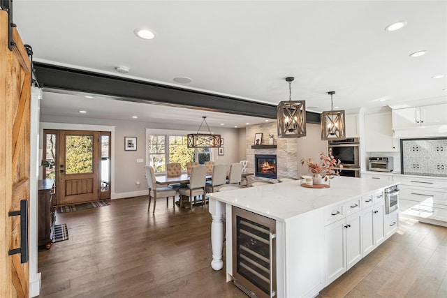 kitchen with a center island, beverage cooler, white cabinets, and wood finished floors